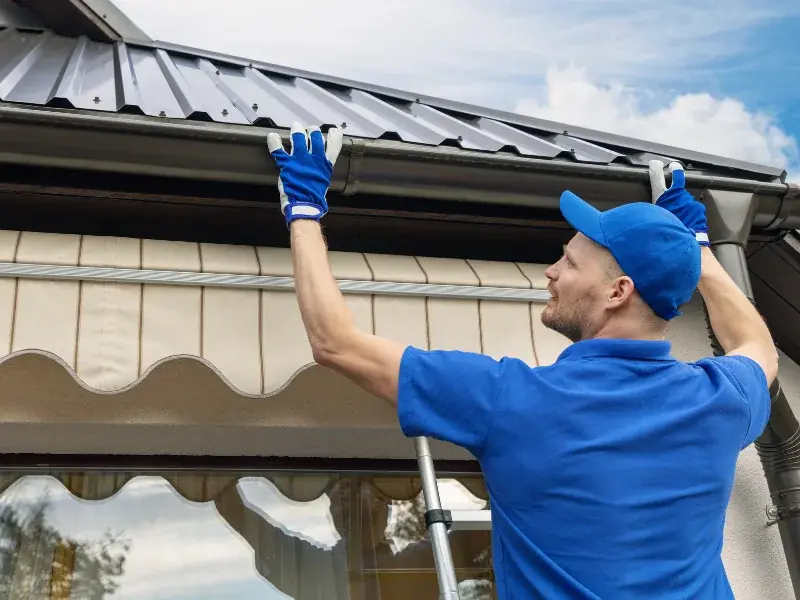 Professional installing seamless aluminum gutters on a New Orleans home